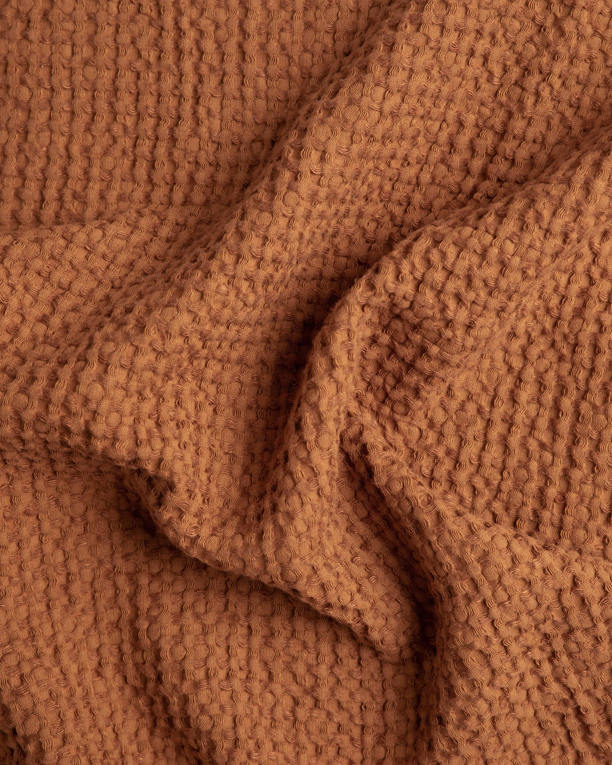 Warm terracotta brown waffle linen–cotton sofa cover styled with neutral décor